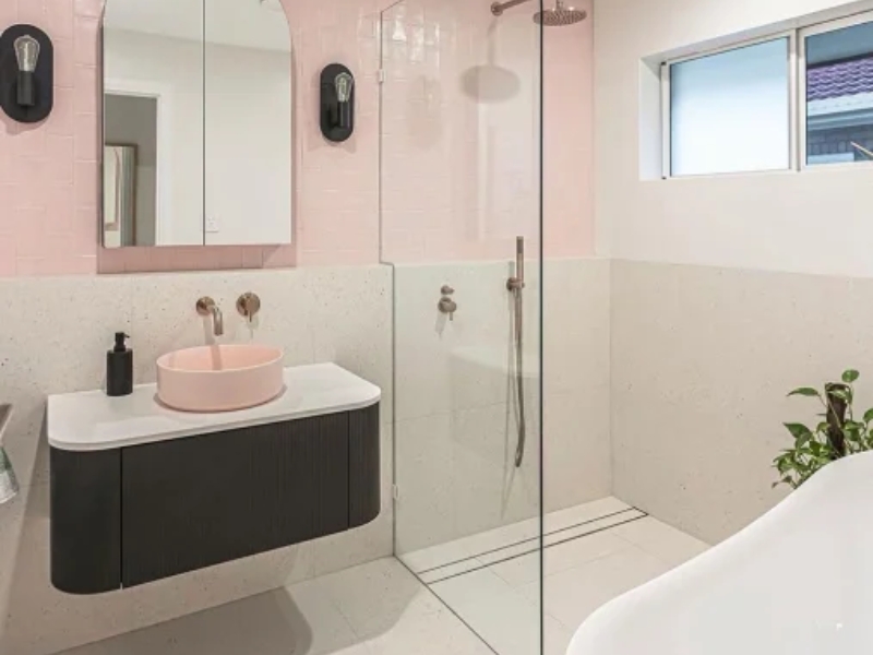 A contemporary bathroom with a glass Walk In Shower Screen beside a pink and white vanity area.
